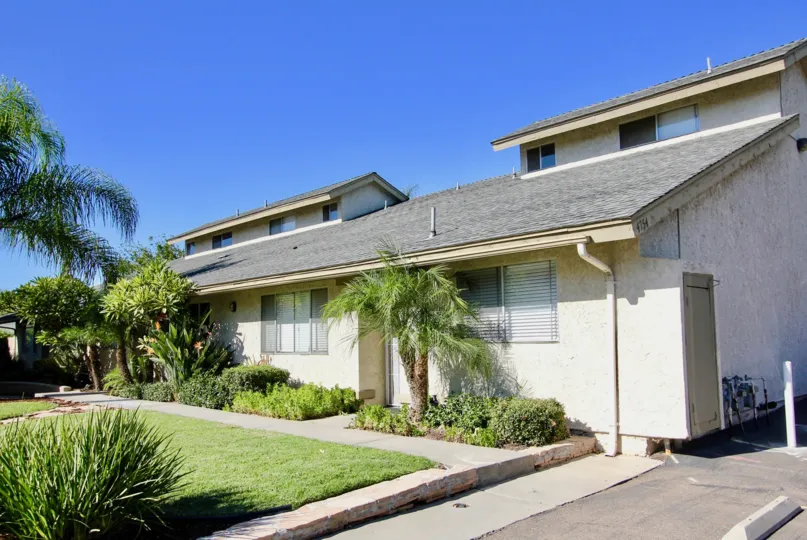 THE HOUSE IN THE WELLINGTON TOWNHOMES WITH THE PATHWAY, METER BOX, GRASS LAND, PLANTS, TREES