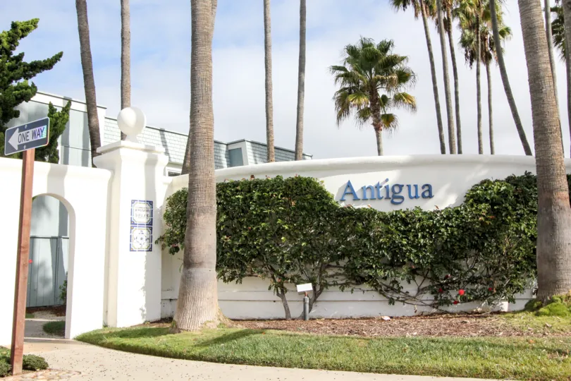 Blue community sign on white wall outside of Antigua Court in Coronado CA