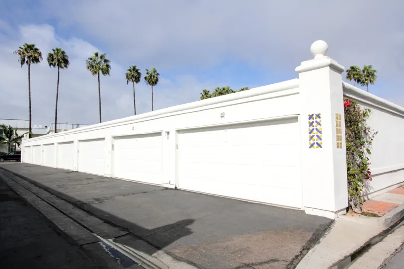 A row of white garage doors with some palm trees in the background during a sunny day in Antigua Court, Coronado, CA
