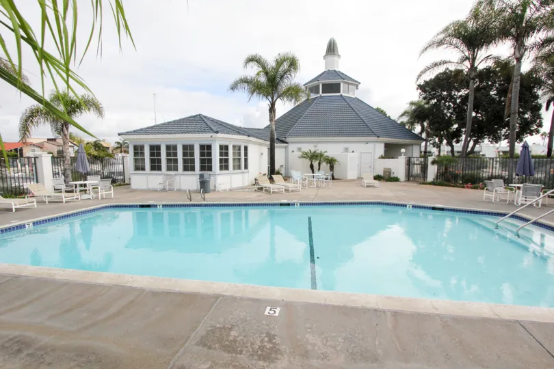 View of the pool area in Bahama Village with back view of house and outdoor chairs.