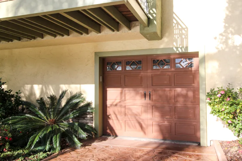 A garage door in a home in the Cayman Cove community of Coronado, California, dappled with sun and shade.