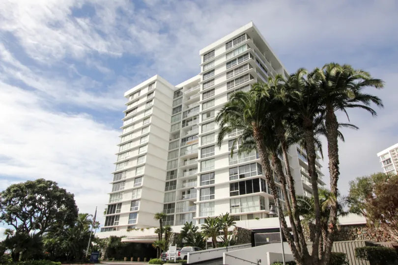 A tall building with some palm trees in the foreground during a sunny day at Coronado Shores, Coronado, CA