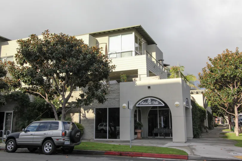 A corner with a shop, a parked car and a tree during a cloudy day in Crownview, Coronado, CA