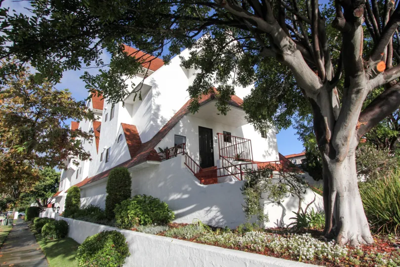Large white residence with large tree in front yard at Island Village in Coronado California