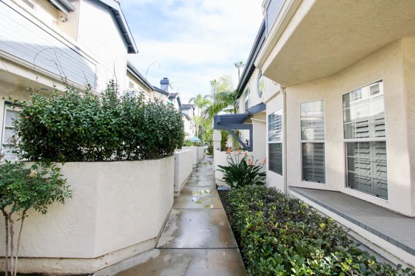 A hallway in between houses with some bushes on the sides at Oxford Park, Coronado, CA