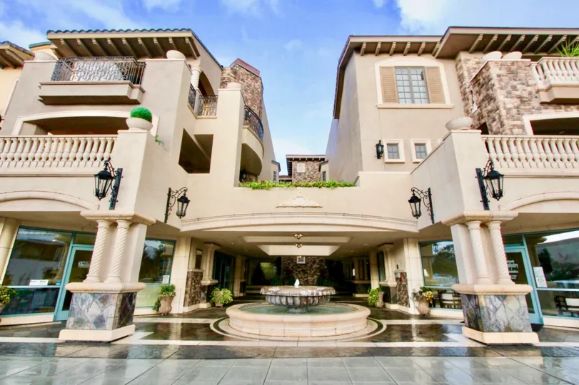 A luxurious apartment building with a fountain during a sunny day in Regatta Bay, Coronado, CA