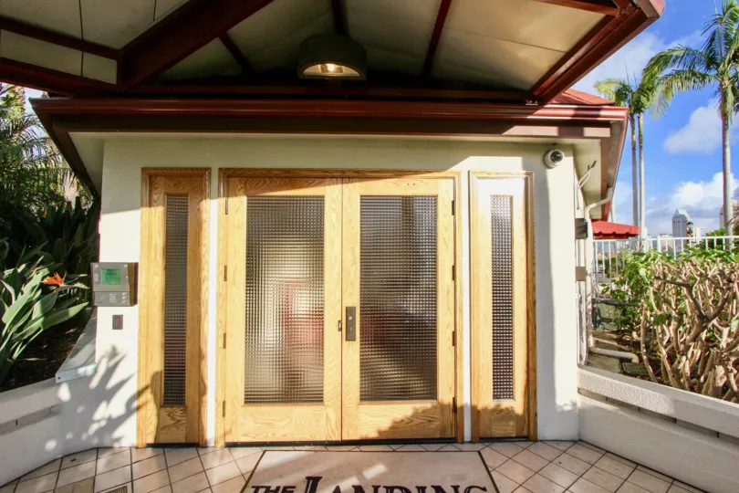 The sun is shining on the doors of The Landing with a beautiful view of palm trees.