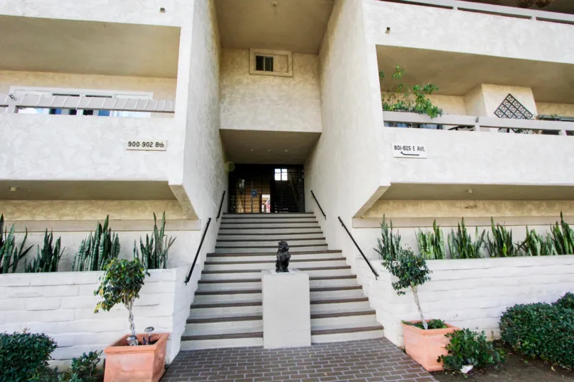 A statue is placed in between the stair of the apartment and flower pot is placed both sides