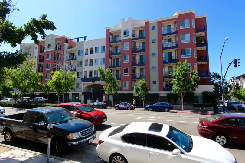 in the sunny day there is a car, and red building and tree