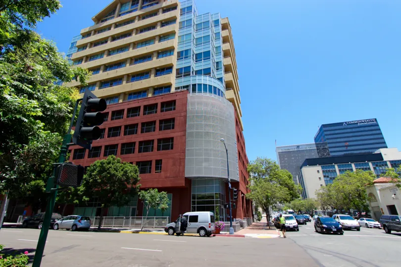 An exterior view of the building at 350 West Ash with red and tan stucco and glass.