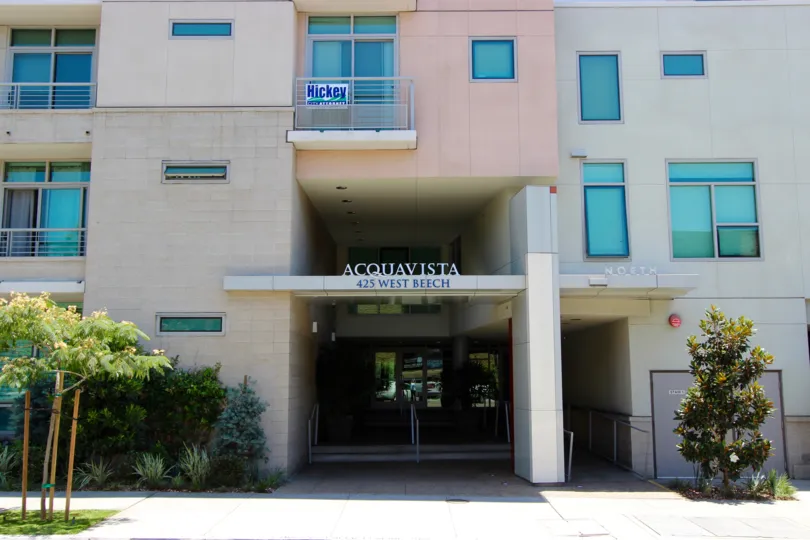 A summer day at the Acqua Vista with the front entrance view with plenty of trees and plants and cool, shady and visually appealing entry leading into the building