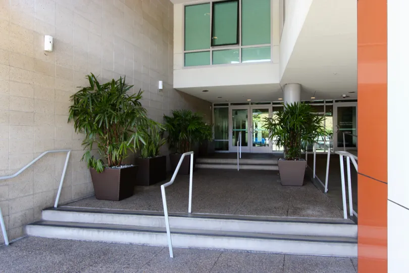Tucked away entryway flanked by potted trees at Acqua Vista in Downtown San Diego, California.