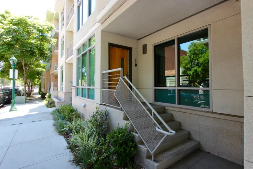A view of the exterior steps and front door of the Acqua Vista office building on a shady street.