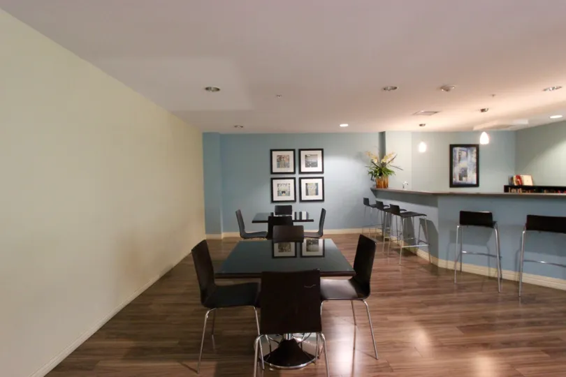 The spacious and clean interior of a cafe in Alicante with hardwood floors and black furniture.