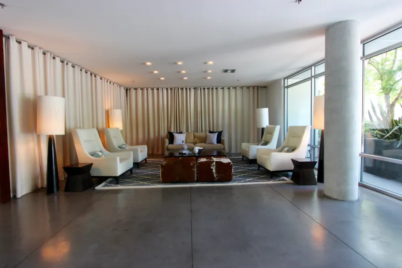 Modern living room with concrete pillars and flooring and large bay windows in the community of Aloft, San Diego, CA
