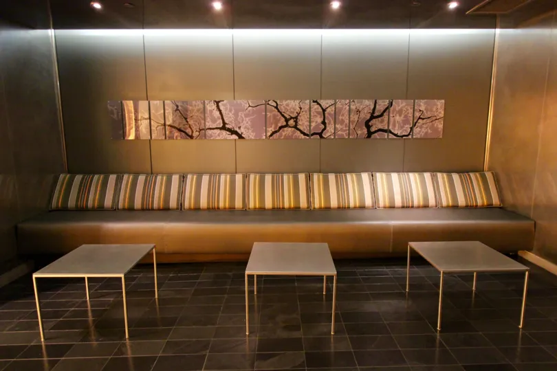 A unique looking tan wall and couch with striped throws and tables.