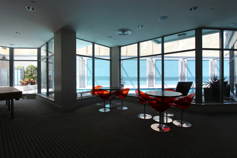 Indoor lounge with tables and chairs by the pool at Aria in downtown San Diego, CA