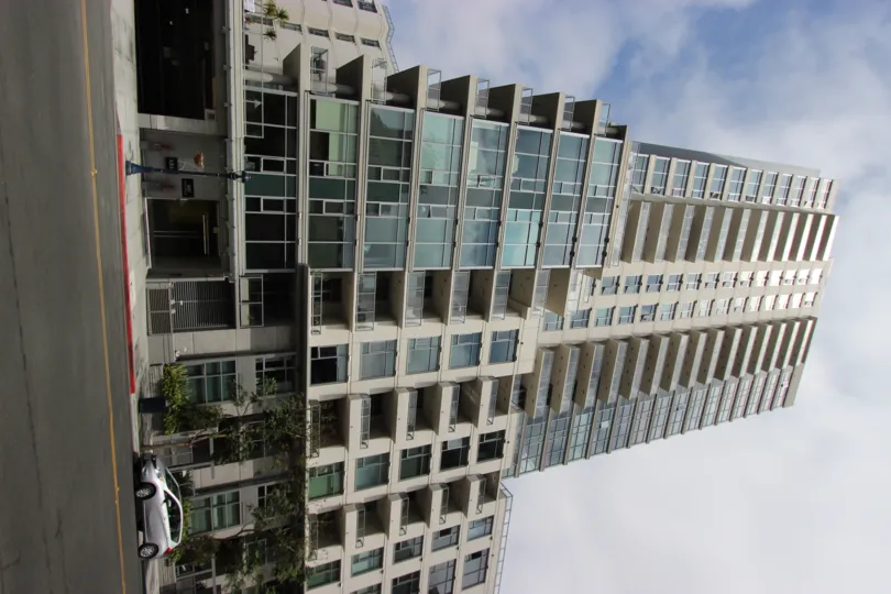 A radiant and bright day at The Aria showcasing the impressive and sophisticated architecture of the tall and magnificent building with a view of the street and parked cars