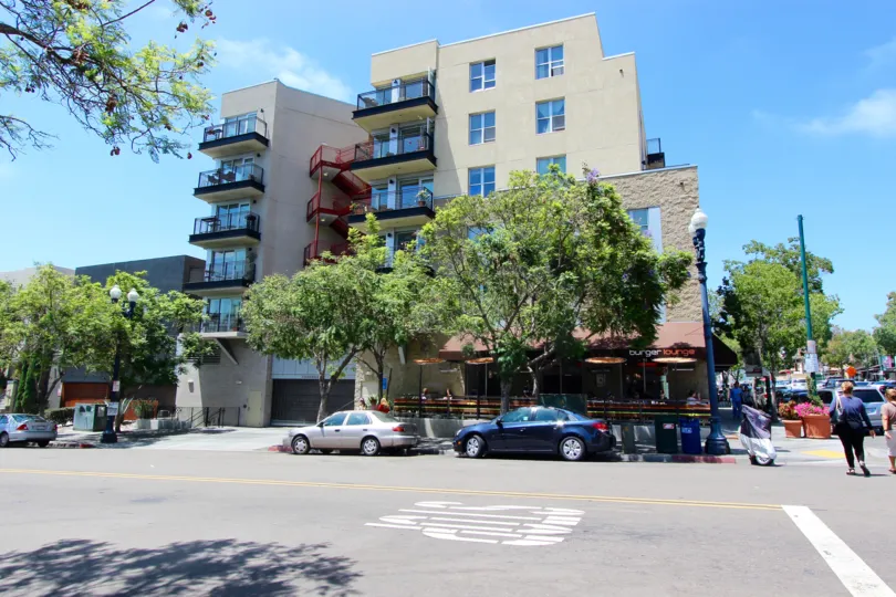 The exterior of the Bella Via building with exterior stairways, glass balconys, and the Burger Lounge in the ground floor.