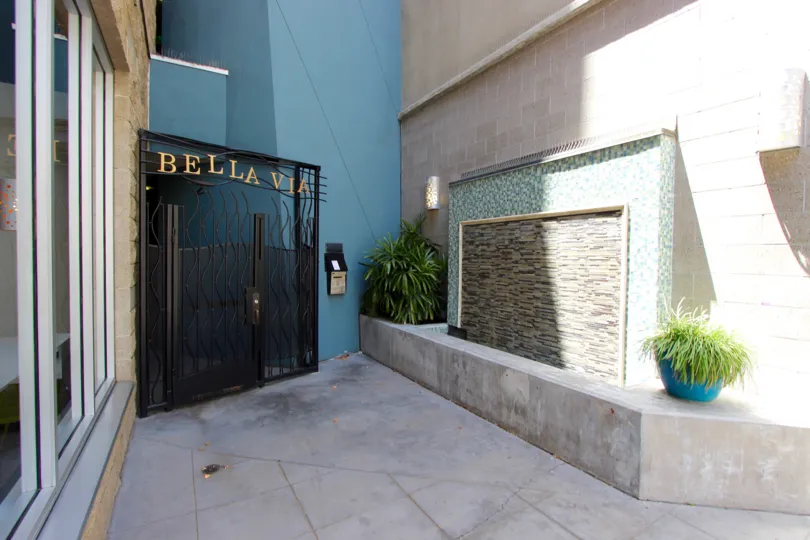 The exterior of the modern Bella Via buiilding including artistic tile work and potted plants and private entrance.