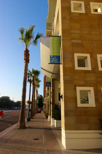 A sunny day in Downtown San Diego's Breeza Community. A sidewalk with trees and an Apartment building.