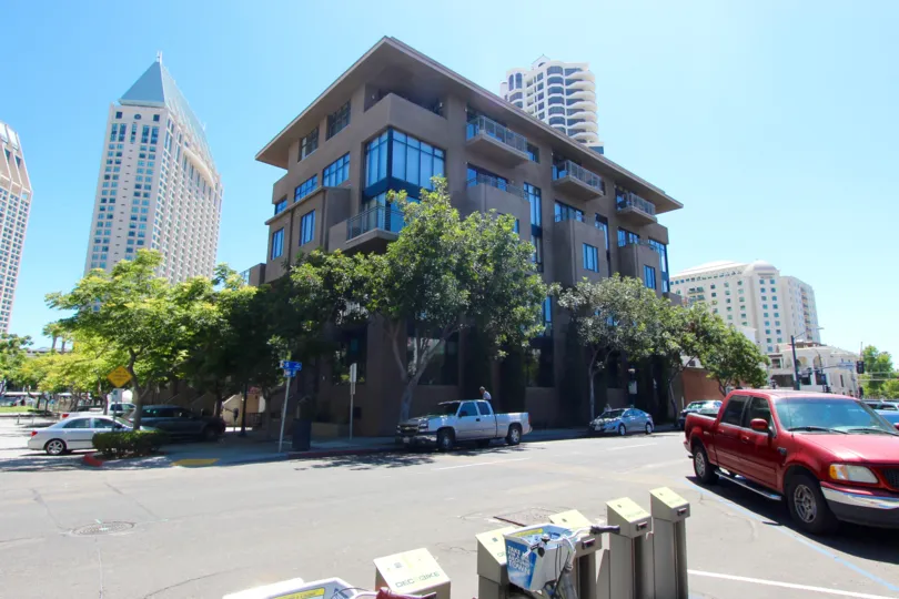 A modern concrete, steel, and glass office building in the Brickyard neighborhood with a shady sidewalk.