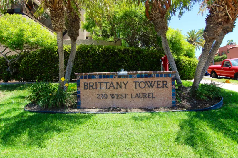 Brown and blue stone sign between two palms inside Brittany Tower at Downtown San Diego CA