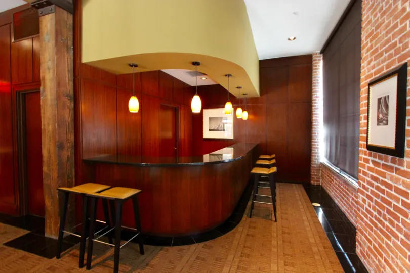 Located in the Cityfront Terrace community of Downtown San Diego, California, this bar is full of character and warmth. The contrasting textures of the dark wood paneling, red brick, and parquet floors bring a ton of life to this small space.
