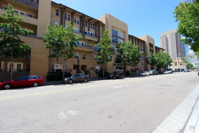 A sunny day outside a building in citywalk with parking in front.