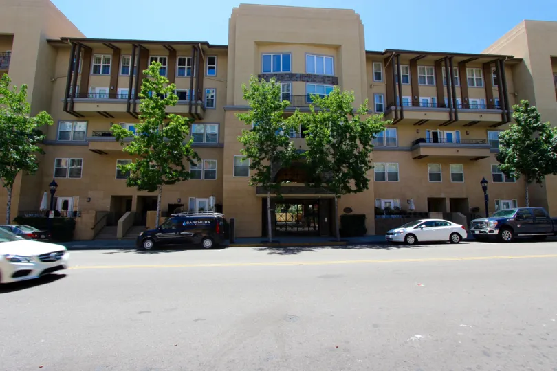 A sunny day in Downtown San Diego California with an apartment building with cars parked out front.
