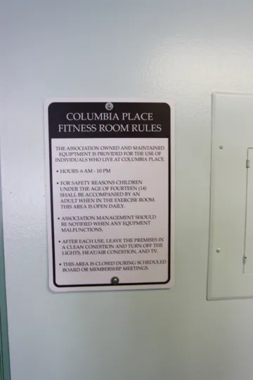 Black and white sign posted to a white wall inside Columbia Place in Downtown Sand Diego CA