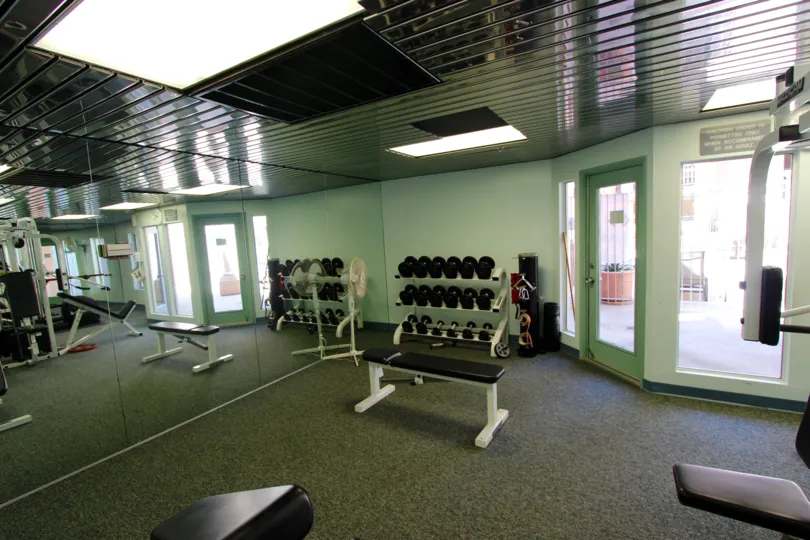 Inside of a Columbia Place gym with free weights and a butterfly machine.