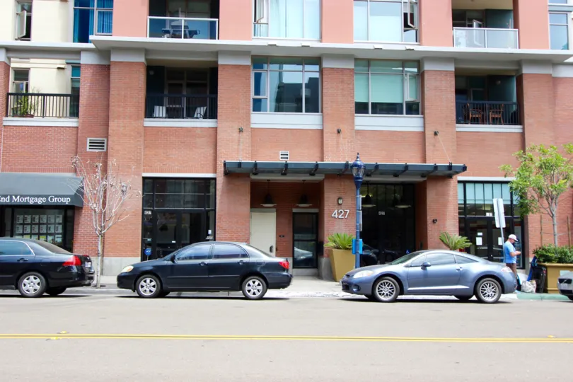 Cars parked below a tall red brick building at Diamond Terrace in Downtown San Diego CA