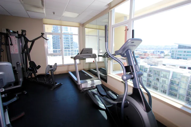 Well-appointed fitness room with massive windows overlooking the city at Diamond Terrace in Downtown San Diego, California.