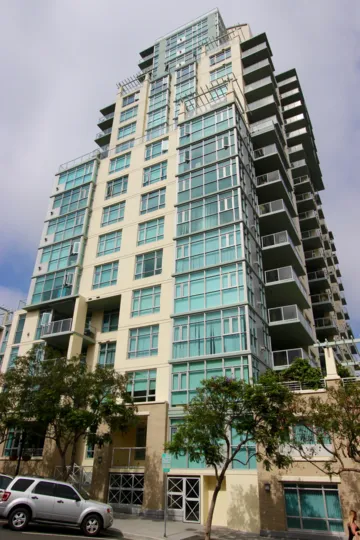 A very tall apartment building against a blue sky in Discovery Downtown San Diego CA.