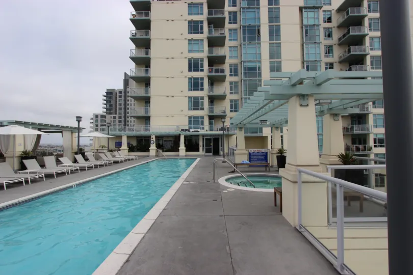 A long narrow pool sits on a rooftop terrace on a cloudy day at Discovery condos