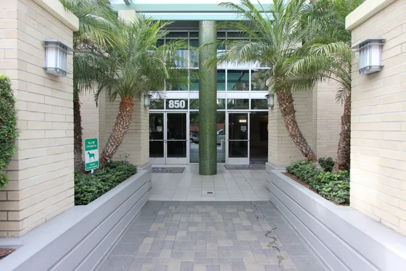 This is the entrance of the hotel which has the glass doors and the both sides were plated the trees in the city of Downtown San Diego