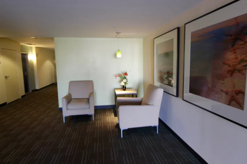 Large waiting room with white walls and beautiful pictures and two seats.