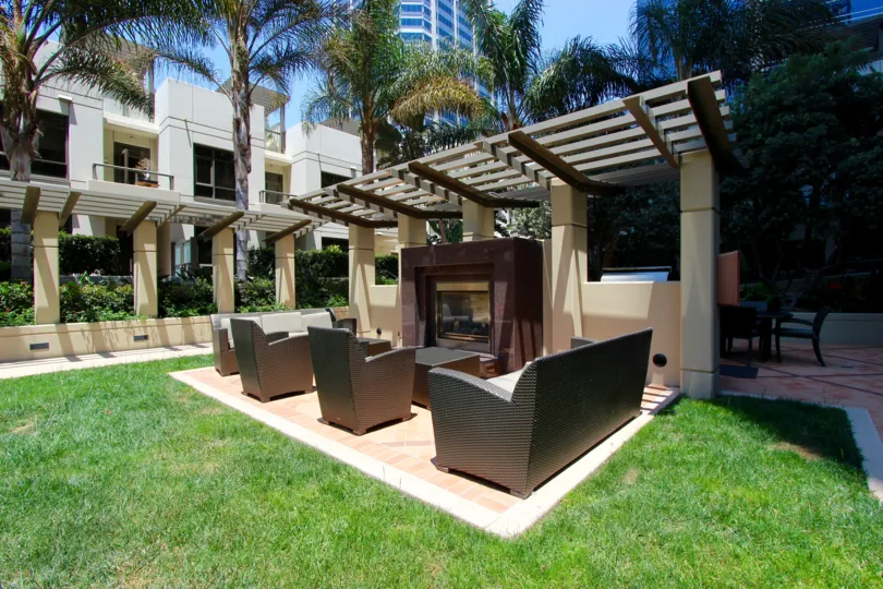 A sunny day outside at a fireplace with chairs and a table.