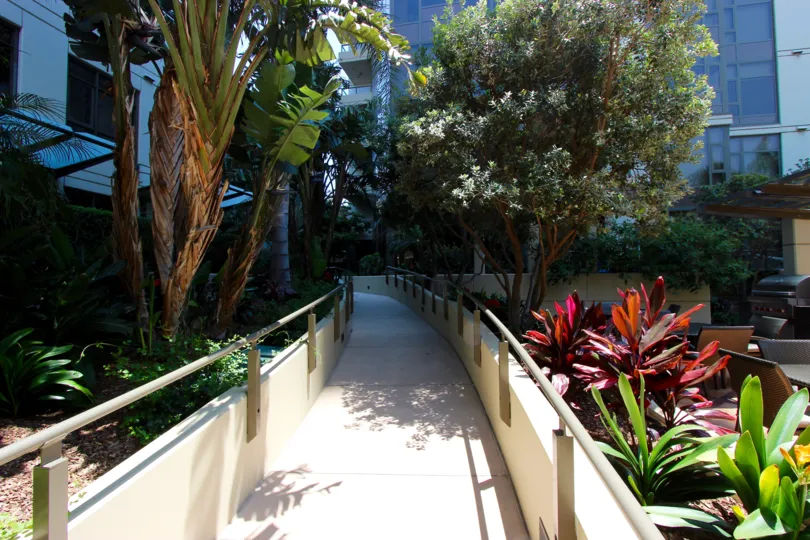 Long walkway with gray railing lined with trees at Electra in Downtown San Diego CA