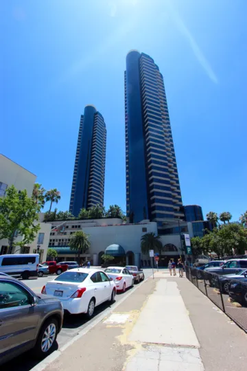 THE BUILDING IN THE HARBOR CLUB WITH CAR PARKING, TREES, PATHWAY, SKY.