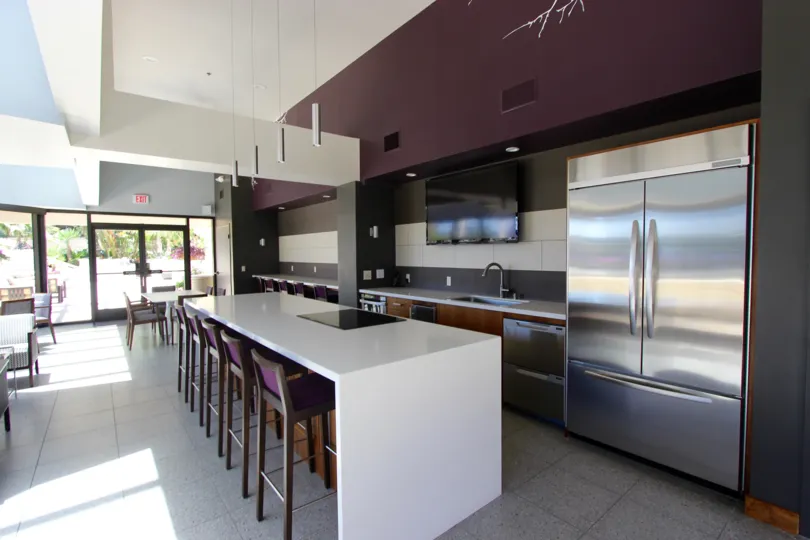 An interior view of the sleek and modern dining lounge at the Harbor Club with stainless steel appliances and plum colored accents.