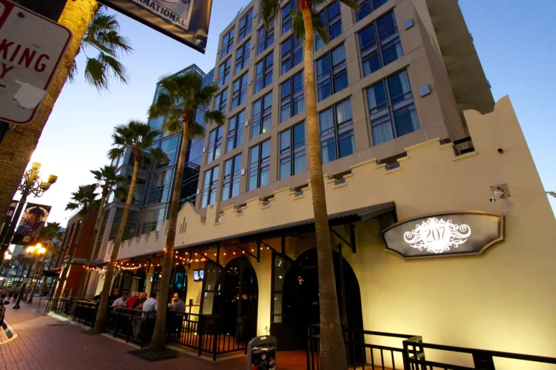 The fabulous hotel was shown which have the lot of rooms and the windows were glassed and the entrance of that many peoples and trees are there in Hardrock