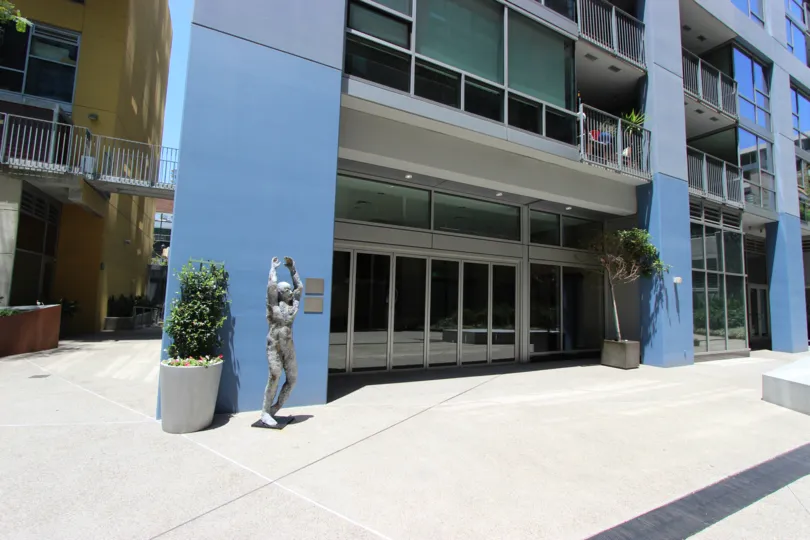 A statue of a man reaching for the sky sits in front of a blue wall in a courtyard at Icon.