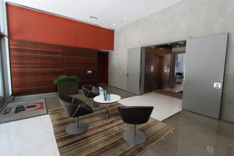 Lounge with chairs to sit and a table with Elevators at Icon