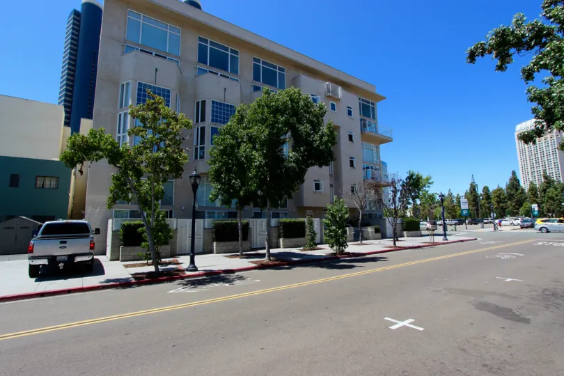 Street view of Island Lofts with trees lining the street, clear blue skk