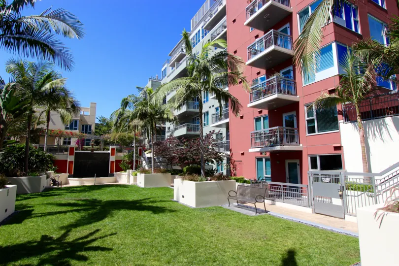 A sunny day in the area of La Vita, outside, bench, palm trees, balconies, condos, grass