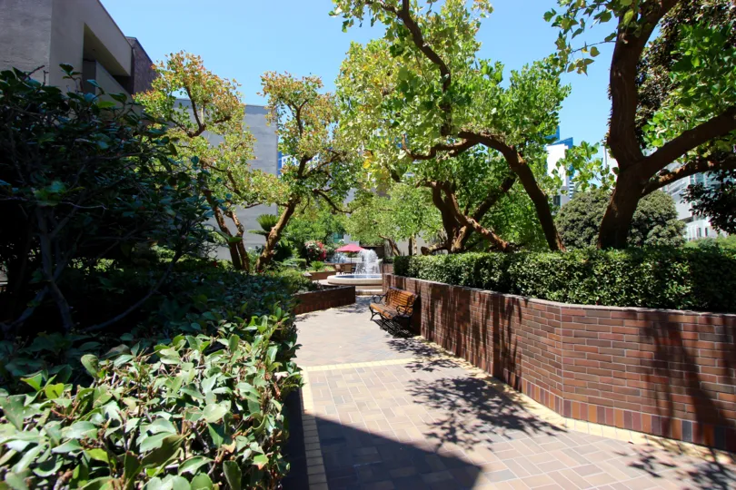A brick walkway through shrubs and trees in Marina Park in downtown San Diego, CA