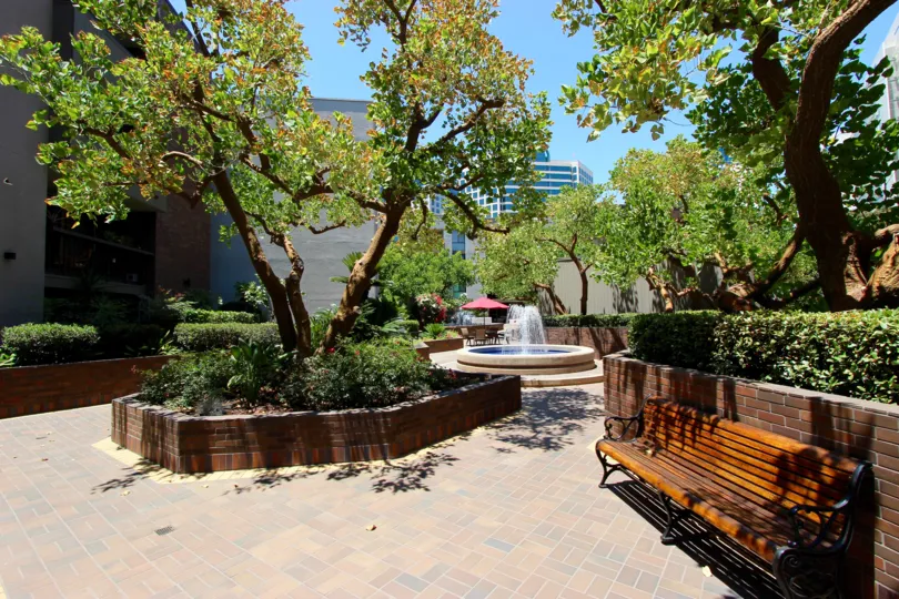 Beautiful sunny day overlooking Marina Park lounge with large water fountain and patio tables.