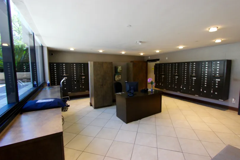 The interior post office of the Marina park building with mail boxes and a reception desk in a spatious room with white tiles.